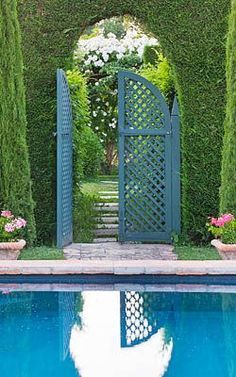 an outdoor pool surrounded by hedges and potted plants