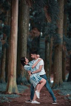 a man and woman are hugging in the woods