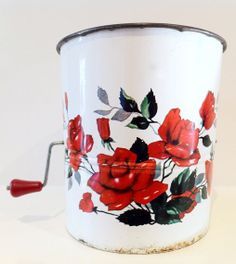 a white bucket with red roses painted on it and a metal handle that is attached to the side