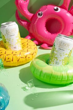 an assortment of drinks and inflatable toys on a table with green background,