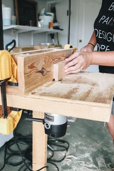 a woman sanding wood on top of a workbench with a router