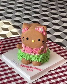 a hello kitty cake sitting on top of a white plate next to a red and white checkered tablecloth