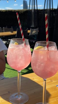 two glasses filled with pink liquid sitting on top of a wooden table next to each other