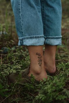 a woman's foot with a flower tattoo on her left ankle, standing in the grass