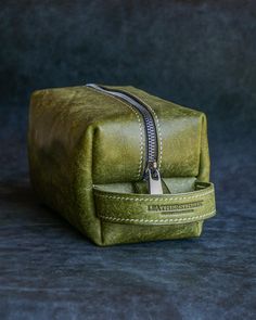 Elevate your travel essentials with our stunning green leather cosmetic case! This stylish and durable toiletry bag is perfect for keeping your items organized on the go. With a secure zipper and premium leather, it's a practical and thoughtful gift for Dad. Whether for daily use or travel, this pouch adds a touch of luxury to any routine. Get ready to travel in style!  DETAILS:  -Premium Italian full grain leather (This leather makes up roughly 10% of all leather available today and you can own Modern Green Rectangular Case Bag, Green Travel Cosmetic Bag With Zipper, Green Zipper Travel Pouch, Portable Green Rectangular Cosmetic Bag, Portable Rectangular Green Cosmetic Bag, Green Rectangular Storage Cases, Green Bags With Zipper Pouch For Storage, Green Travel Bag With Zipper Pouch, Green Leather Rectangular Case Bag