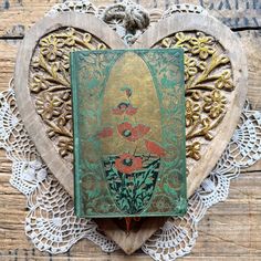 an old book is sitting on a doily in the shape of a heart