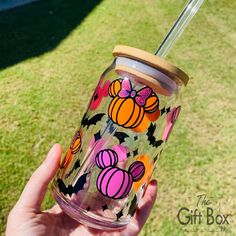 a person holding up a glass with a straw in it and pumpkins on it