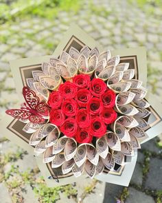 a bouquet made out of rolled up money with red roses in the shape of a heart