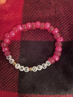 a pink beaded bracelet with white letters on it and the word, be the bee