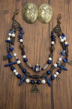 a necklace and earring set with blue beads on a wooden table next to a pair of earrings