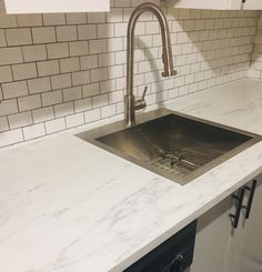 a kitchen sink sitting under a faucet on top of a white countertop