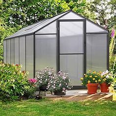 a small greenhouse in the middle of some flowers