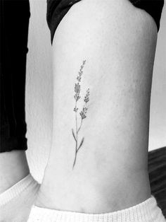 a small lavender flower tattoo on the back of a woman's lower leg,