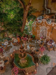 an aerial view of a restaurant with tables, chairs and fountain in the center surrounded by greenery