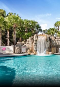 a large pool with a waterfall next to palm trees