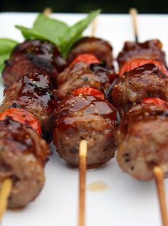 several skewered meats with ketchup and green leaves on the side