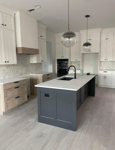 a large kitchen with an island in the middle of it and white cabinets on both sides