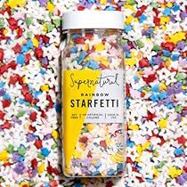 sprinkles are scattered around a jar of starfetti on a colorful surface