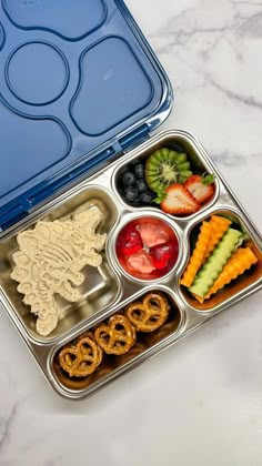 a bento box filled with fruit, pretzels and crackers in it