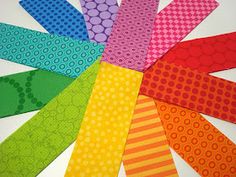 colorful paper strips arranged in a circle on a white table top with dots and circles