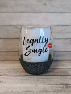 a wine glass with the words legally single printed on it sitting on a wooden table