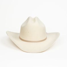 Elevate your wardrobe with our white Karina Cowboy hat. Inspired by old western films and a classic old pair of boots, this hat comes in a natural white colorway and trimmed with cream cord. Like all of our hats, the Karina is hand-pressed by our artisan partners in Ecuador and made from sheep’s wool. Wool makes for the perfect adventure hat leaving you warm in the winter or dry in the summer. Style Notes 100% Ecuadorian Sheep's Wool 4" Curved Brim with Creased Crown Cotton Ribbon finishing Cust Adventure Hat, White Bucket Hat, Old Western, White Cafe, All Natural Makeup, Western Film, Rancher Hat, Straw Cowboy Hat, Cotton Ribbon