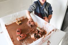 a little boy that is standing in front of a box with some dirt on it