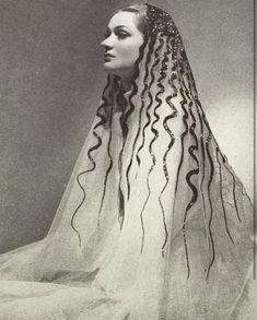 an old photo of a woman with long hair wearing a veil and headdress