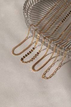 several gold chains hang from the side of a glass bowl on a white tablecloth