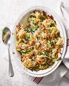 a white bowl filled with food on top of a table next to a silver spoon