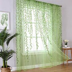 a green curtain hanging in front of a window next to a potted plant