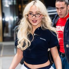 a blonde woman with glasses walking down the street