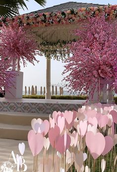 some pink flowers and trees in front of a gazebo with white hearts on it