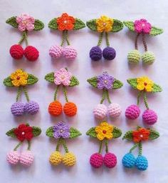 crocheted cherries with flowers and leaves are arranged on a white tablecloth