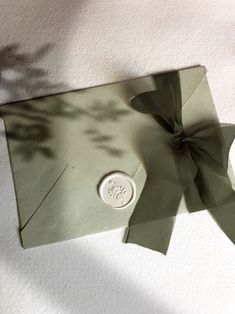 an open envelope with a bow on the front and a wax stamp on the back