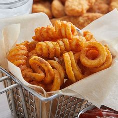 a basket filled with fried onion rings next to dipping sauce