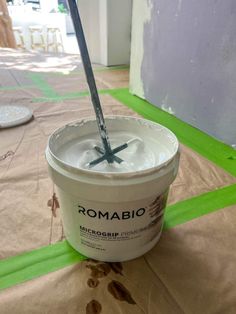 a bucket of white paint sitting on top of a green floor next to a wall