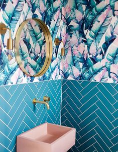 a bathroom with blue and pink wallpaper, gold faucet, sink and mirror