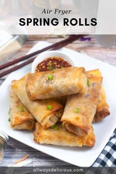 spring rolls on a white plate with dipping sauce and chopsticks in the background