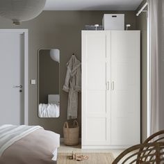 a bedroom with a bed, mirror and white cupboards on the wall in front of it