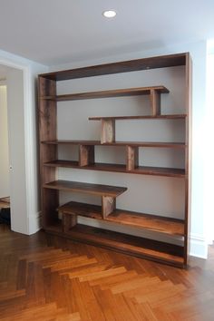 an empty room with wooden shelves and hard wood flooring