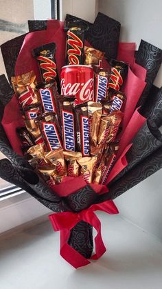 a bouquet of chocolates and candy wrapped in red paper on a window sill