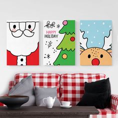 two christmas paintings hang on the wall above a red checkered couch