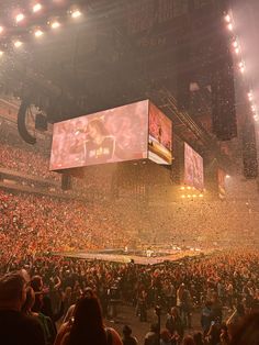 a large crowd at a concert in front of a big screen