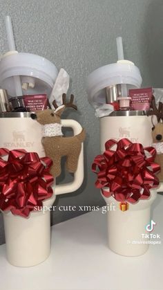 two coffee mugs decorated with bows and reindeer decorations are sitting on a counter next to each other