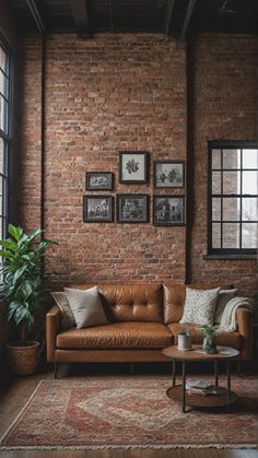 a living room with brick walls and leather couches in front of a window, potted plant on the side table