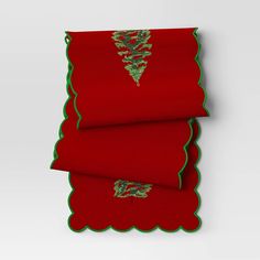 two folded red towels with green trim on each side and a decorative design on the bottom