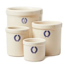 four white pots with blue designs on them sitting next to each other in front of a white background