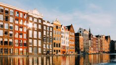 several buildings are reflected in the water on a sunny day with blue sky and clouds