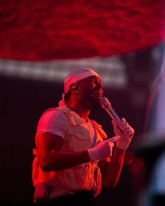 a man standing on stage holding a microphone in his right hand and singing into the microphone